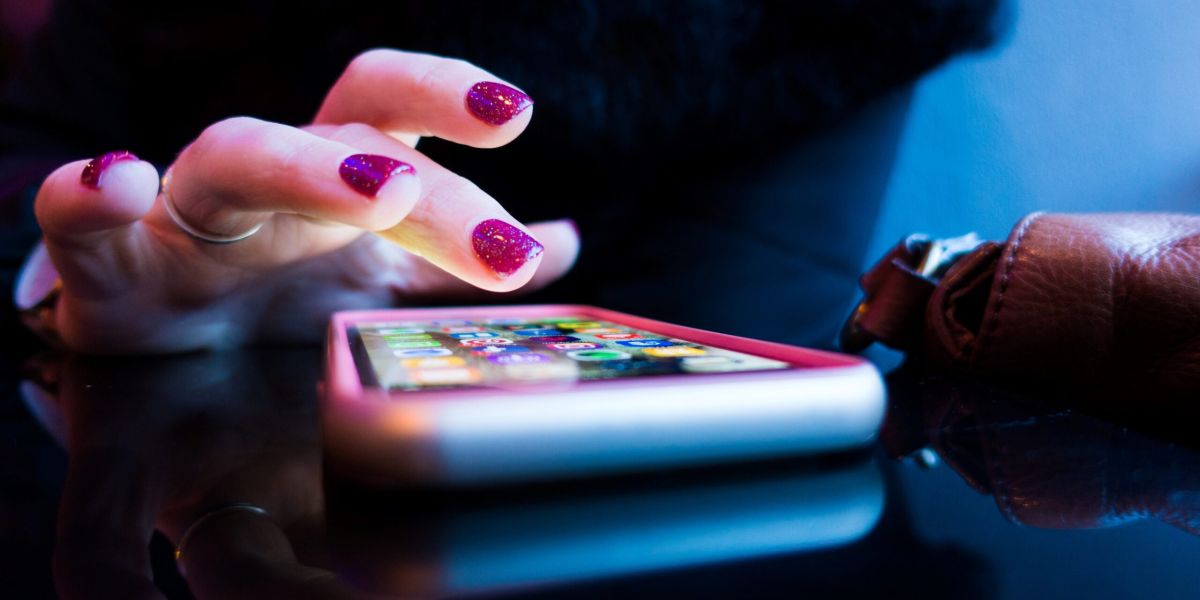 person using black smartphone with gray and pink case