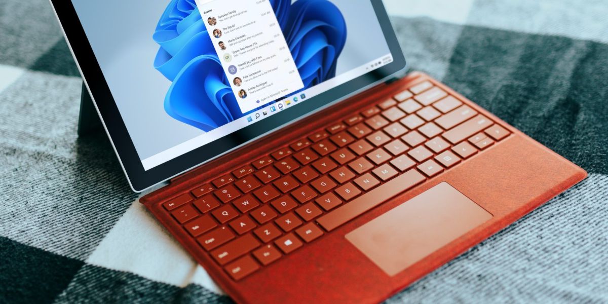 Red Surface laptop on a checkered bed by a window