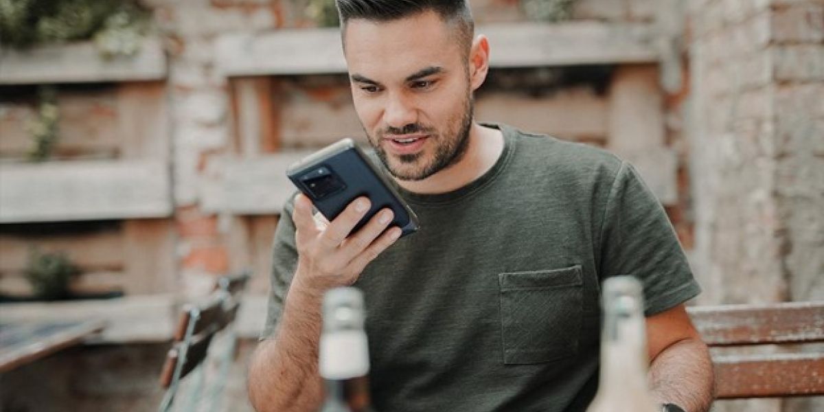 man in gray crew neck long sleeve shirt holding black smartphone