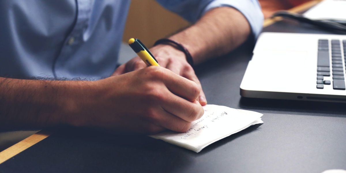 Free Person Writing on Paper Using Yellow and Black Pen Stock Photo