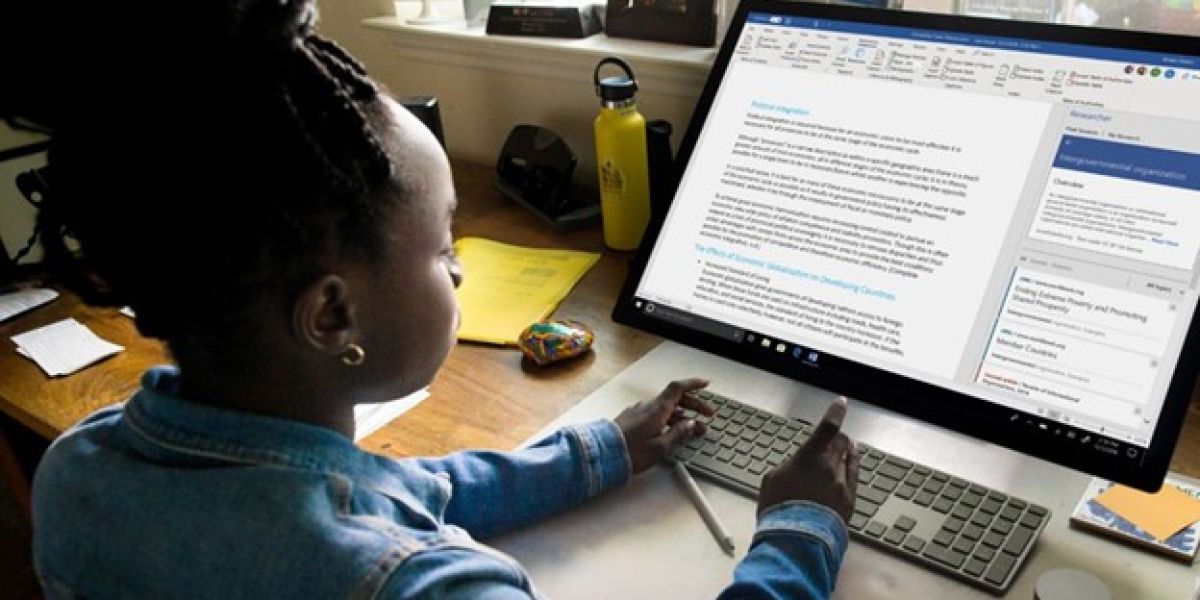 Young person using a wireless keyboard to work on a document in Microsoft Word on a large desktop monitor